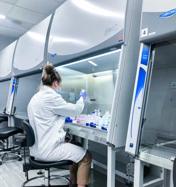female scientists in research lab working under a fume hood with tissue cell culture
